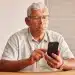 Idoso utilizando smartphone em casa, representando o medo de golpes digitais entre pessoas acima de 60 anos em São Paulo.