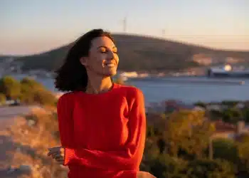 Mulher sorrindo ao ar livre durante o pôr do sol representando hábitos positivos para uma vida mais equilibrada.