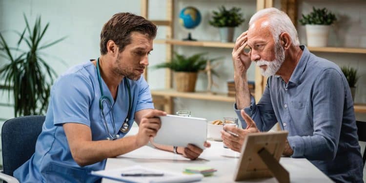 Enfermeiro homem mostra tablet para paciente idoso em consulta — homens em profissões de cuidado