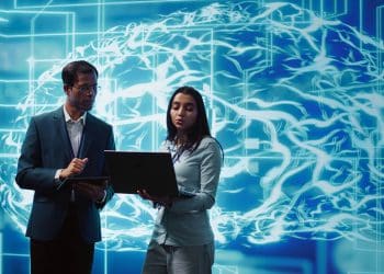 Profissionais analisando dados em notebook diante de representação visual de inteligência artificial e redes neurais digitais