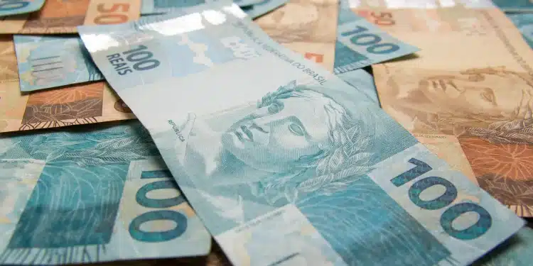 Notas de real em destaque, incluindo cédulas de 100 e 50 reais, ilustrando os pagamentos do INSS de março de 2026.