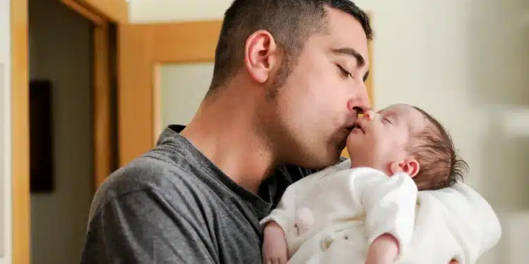 Pai segurando e beijando um recém-nascido, representando o fortalecimento do vínculo familiar após aprovação do Senado para ampliar gradualmente a licença paternidade no Brasil.