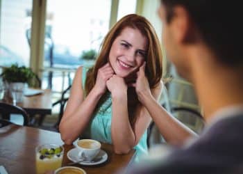 Linguagem corporal: mulher com olhar fixo e sorriso genuíno demonstrando interesse durante conversa