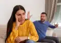Imagem de um casal em uma discussão, com a mulher visivelmente desconfortável e o homem gesticulando em um ambiente doméstico, representando a dinâmica de um relacionamento abusivo, como o gaslighting.