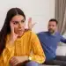 Imagem de um casal em uma discussão, com a mulher visivelmente desconfortável e o homem gesticulando em um ambiente doméstico, representando a dinâmica de um relacionamento abusivo, como o gaslighting.