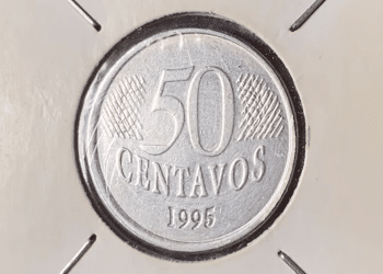 Close-up de uma moeda de 50 centavos de 1995 da primeira família do Real, protegida em um suporte para colecionador (coin holder).