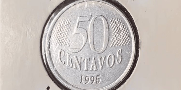 Close-up de uma moeda de 50 centavos de 1995 da primeira família do Real, protegida em um suporte para colecionador (coin holder).