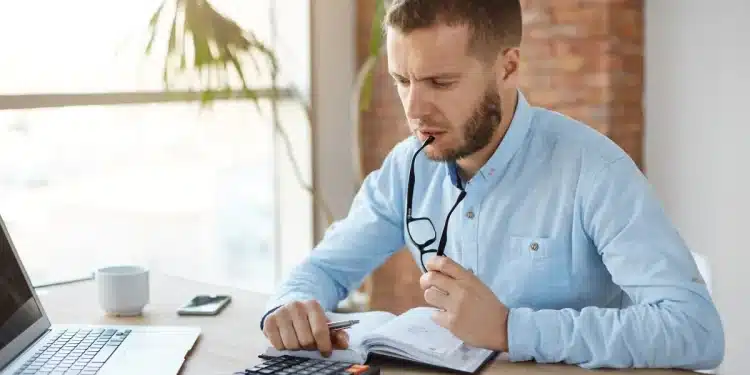 Homem analisando contas e fazendo cálculos financeiros no notebook para negociar dívidas bancárias no mutirão de renegociação
