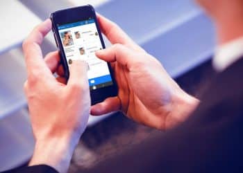 Pessoa navegando em um aplicativo de redes sociais no smartphone, ilustrando a interação digital.