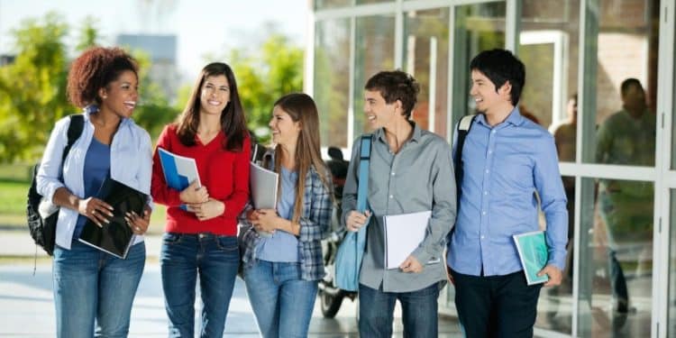 Grupo de estudantes universitários caminhando e conversando em um campus, representando oportunidades de estágio para alunos de Direito e Economia.