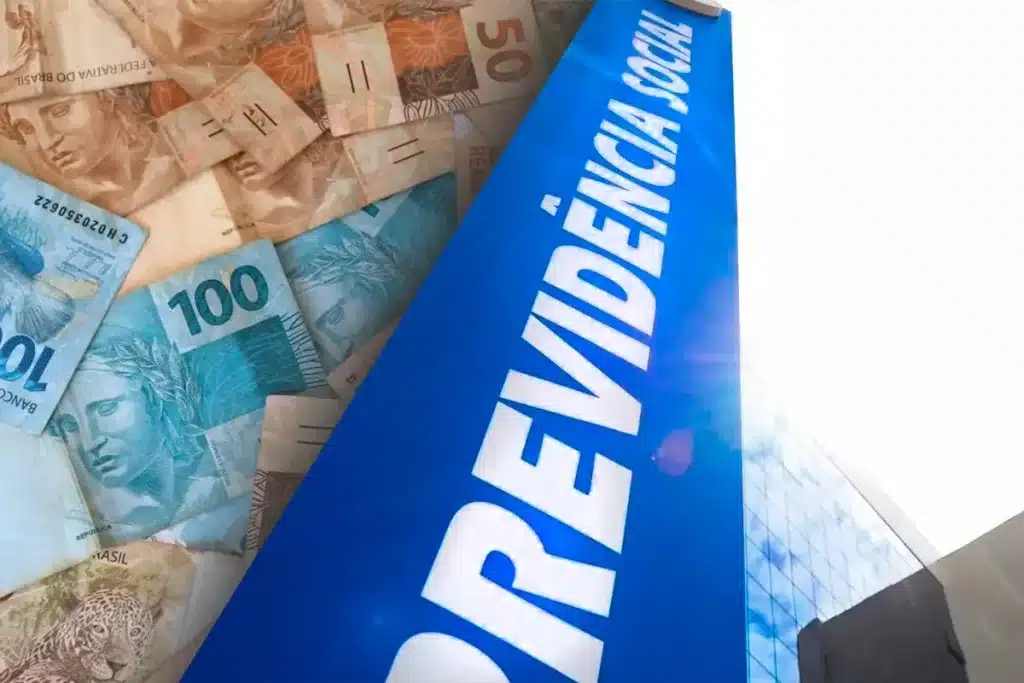 Logo da Previdência Social com cédulas de R$ 100, R$ 50 e R$ 10 ao fundo, representando o pagamento do Benefício de Prestação Continuada (BPC) do INSS.