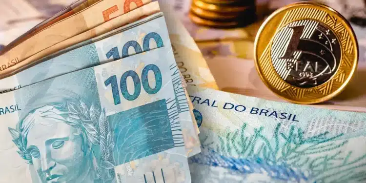 Notas e moedas do real brasileiro, incluindo cédulas de R$100 e R$50 e uma moeda de R$1, representando o contexto de pagamentos do INSS em 2026.