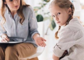 Menina em sessão de terapia demonstra comportamento introspectivo associado à maturidade precoce e parentalização infantil.