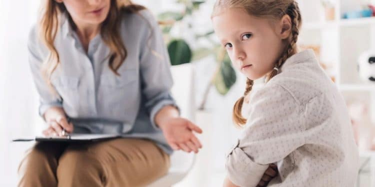 Menina em sessão de terapia demonstra comportamento introspectivo associado à maturidade precoce e parentalização infantil.