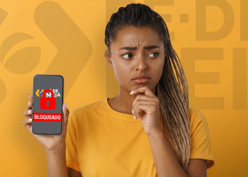 Mulher jovem segura celular mostrando tela de bloqueio do benefício Pé-de-Meia.