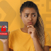 Mulher jovem segura celular mostrando tela de bloqueio do benefício Pé-de-Meia.