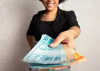 Estudante segura cédulas de reais simbolizando a bolsa de R$ 1.050 do Pé-de-Meia Licenciaturas em 2026.