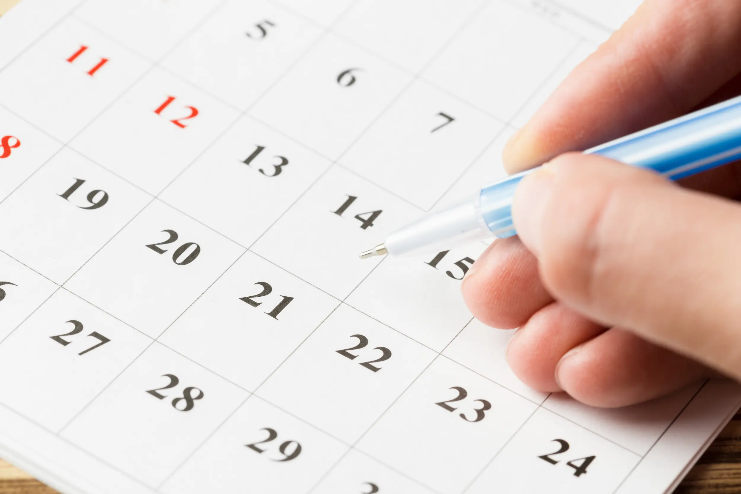 Pessoa marcando datas em um calendário para organizar atividades durante os feriados de abril.