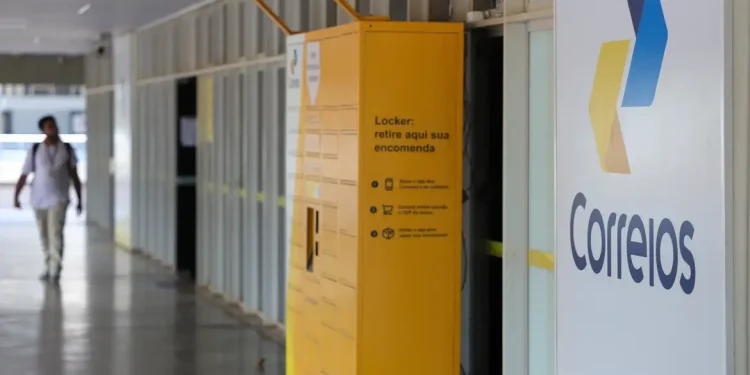 Fachada de unidade dos Correios com logomarca e locker amarelo para retirada de encomendas, representando o processo seletivo do programa jovem aprendiz Correios 2026, com 548 vagas e inscrições gratuitas.