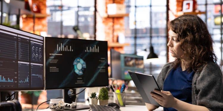 Profissional de IA analisando dashboards e dados em monitores representando funções de inteligência artificial nas empresas