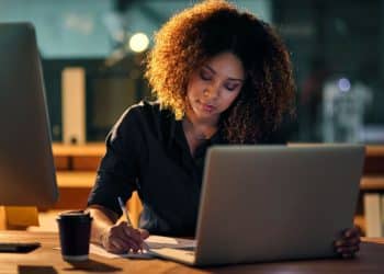 Profissional trabalhando até tarde, focado em tarefas relacionadas à tecnologia e inteligência artificial, áreas em ascensão no futuro.