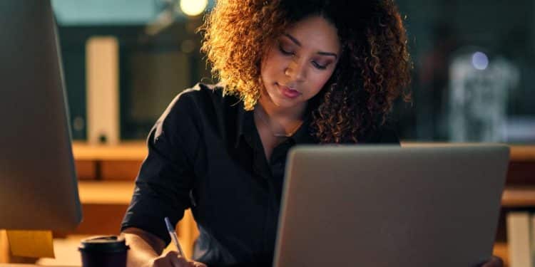 Profissional trabalhando até tarde, focado em tarefas relacionadas à tecnologia e inteligência artificial, áreas em ascensão no futuro.