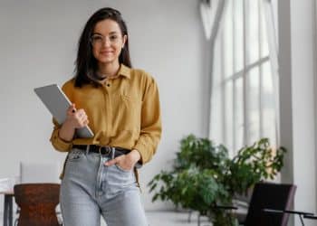 Profissional segurando um tablet em ambiente de trabalho moderno, representando mulheres que atuam na defesa de direitos e na promoção da igualdade de gênero.
