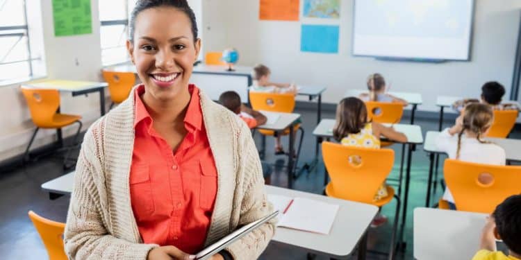 Professora entrega atividade a alunos em sala de aula enquanto projeto de lei debate adicionais de insalubridade para docentes.