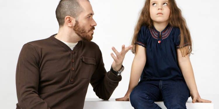 Um homem adulto com expressão de cobrança gesticula enquanto fala com uma menina; a criança desvia o olhar com semblante de cansaço e frustração, representando a imaturidade emocional parental.