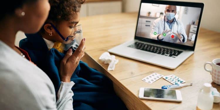 Mãe e filha durante consulta médica online, com a criança usando máscara de oxigênio enquanto recebe atendimento de um pediatra virtual.