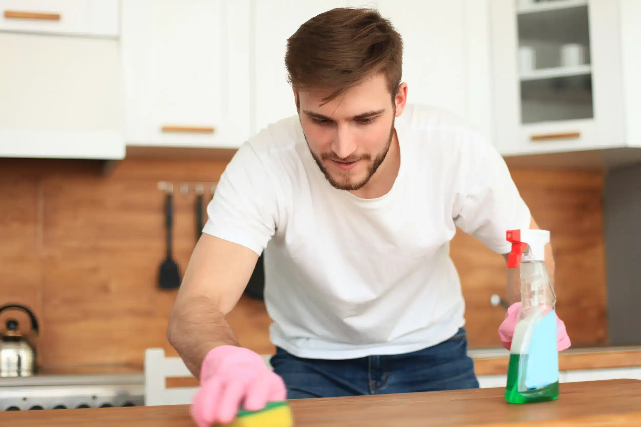 Homem limpando uma mesa repetidamente com luvas e produto de limpeza, ilustrando comportamentos compulsivos associados ao TOC.