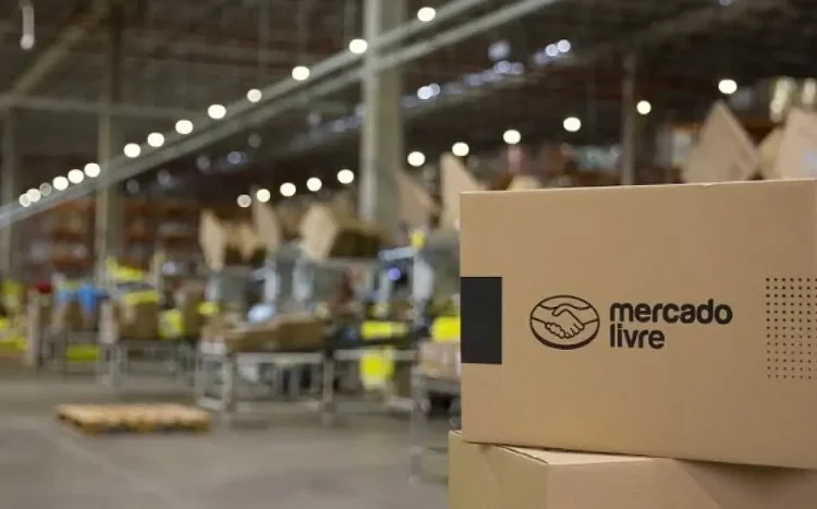 Caixa com logotipo do Mercado Livre em galpão com funcionários ao fundo