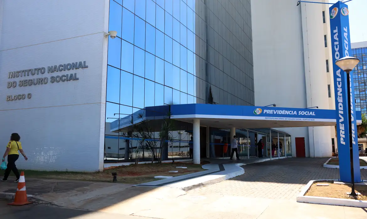 Fachada do edifício sede do Instituto Nacional do Seguro Social com placa da Previdência Social, representando a antecipação do 13º salário do INSS prevista para abril e maio de 2026