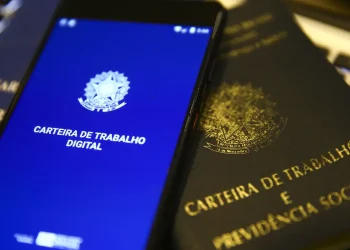 Carteira de Trabalho física e digital ao lado de teclado, representando o prazo de pagamento do salário garantido pela CLT aos trabalhadores brasileiros