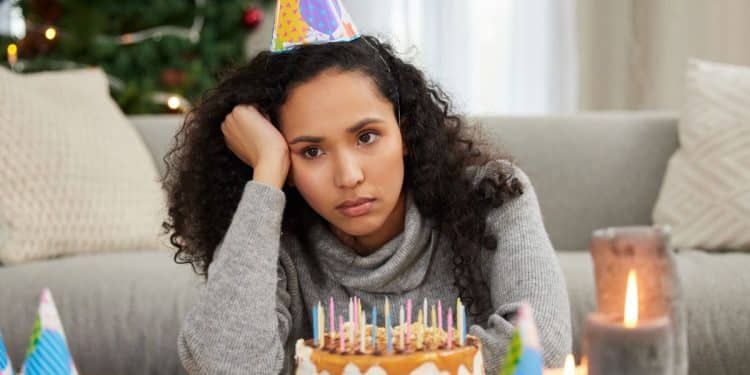 Jovem triste com bolo de aniversário.