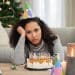 Jovem triste com bolo de aniversário.