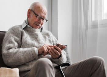 Idoso mexendo no celular.