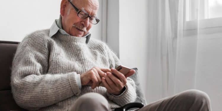 Idoso mexendo no celular.