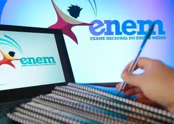 Estudante anotando em caderno enquanto acessa informações do Enem em notebook.