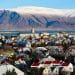 Vista panorâmica de cidade na Islândia com casas coloridas e montanhas nevadas ao fundo, representando qualidade de vida e bem-estar.