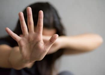 Mulher fazendo sinal de parada, representando a luta contra a violência doméstica e as novas leis sancionadas pelo presidente Lula.