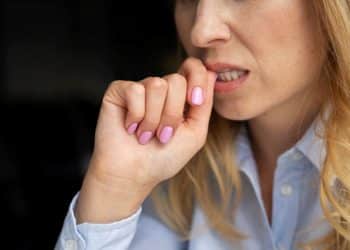 Pessoa roendo a unha em momento de tensão, comportamento associado à ansiedade e estresse.