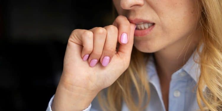 Pessoa roendo a unha em momento de tensão, comportamento associado à ansiedade e estresse.
