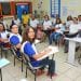 Turma de adultos em sala de aula, com professora ao fundo, representando oportunidades de concurso público para pedagogos.