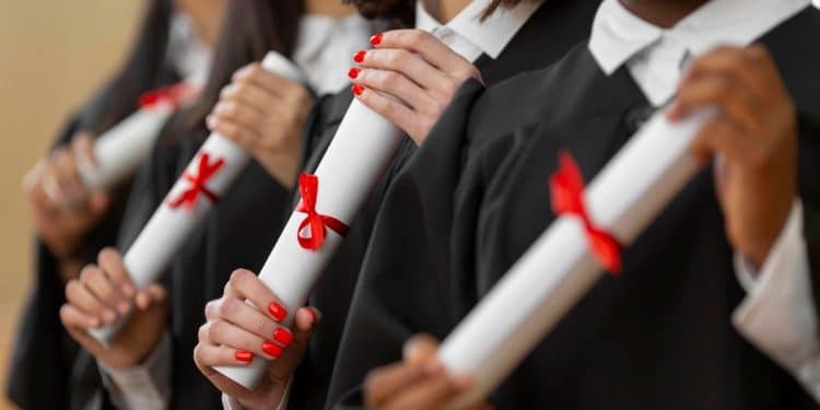 Formandos seguram diplomas com fitas vermelhas em cerimônia.