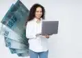Profissional sorrindo usa notebook diante de notas de R$ 100, em imagem sobre altos salários CLT no Brasil.