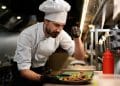 Chef ajustando prato na cozinha profissional, representando a importância do trabalho dos cozinheiros e gastrônomos, profissões em processo de regulamentação no Senado.