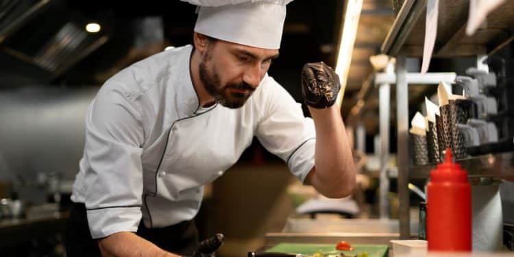Chef ajustando prato na cozinha profissional, representando a importância do trabalho dos cozinheiros e gastrônomos, profissões em processo de regulamentação no Senado.