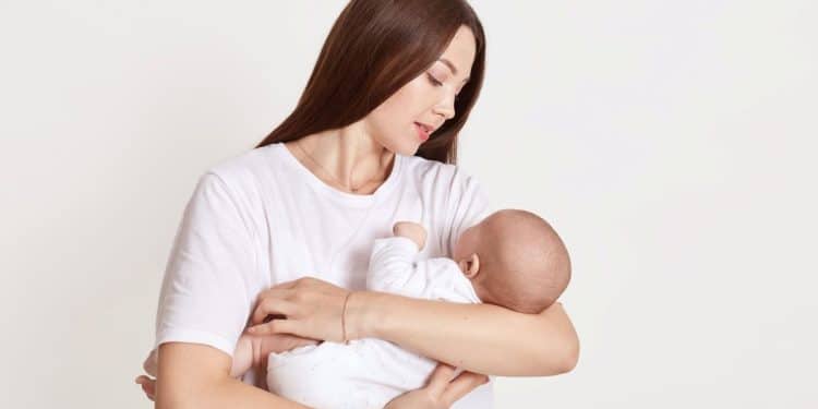 Mãe segura bebê recém-nascido em momento de conexão.