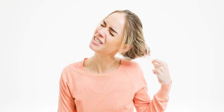 Mulher puxando seus próprios fios de cabelo.